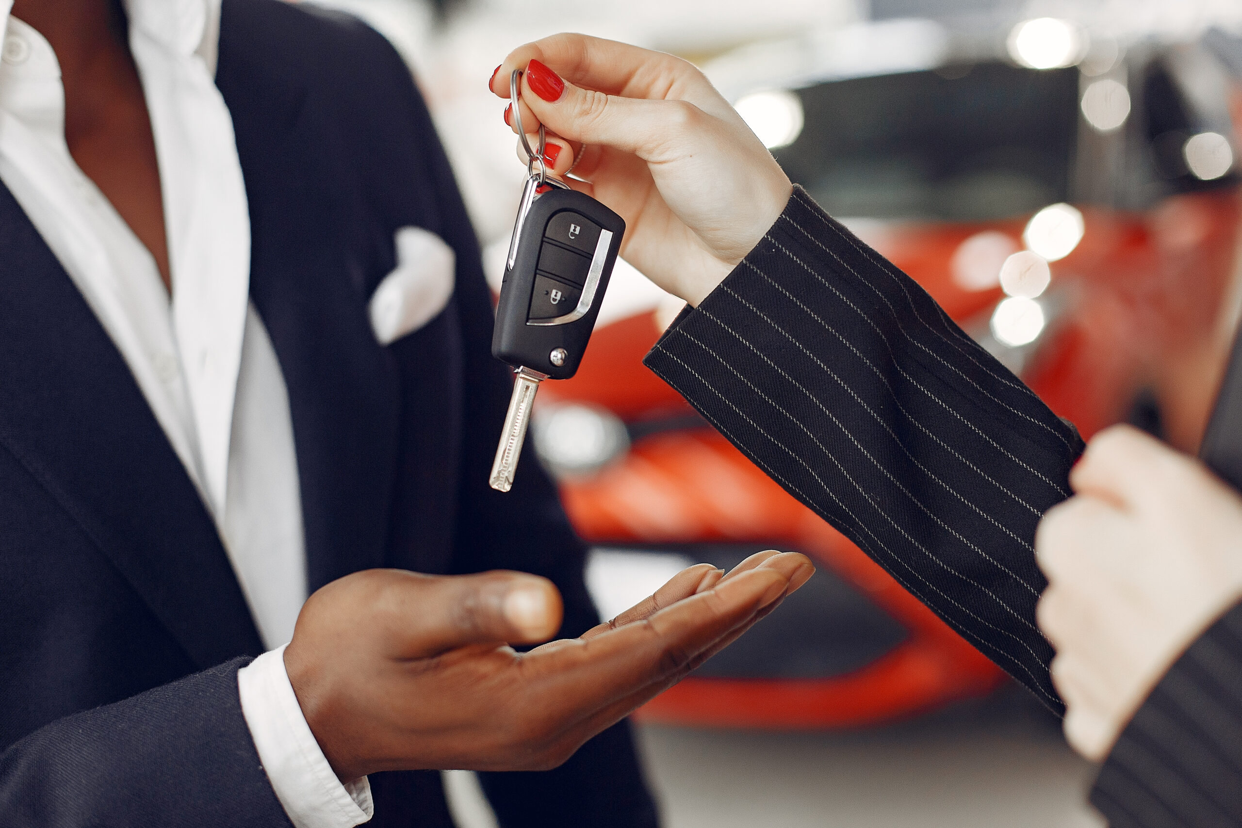 Man buying the car. Assistant helps to choose a car. Businessman in a car salon. Black male in a suit.